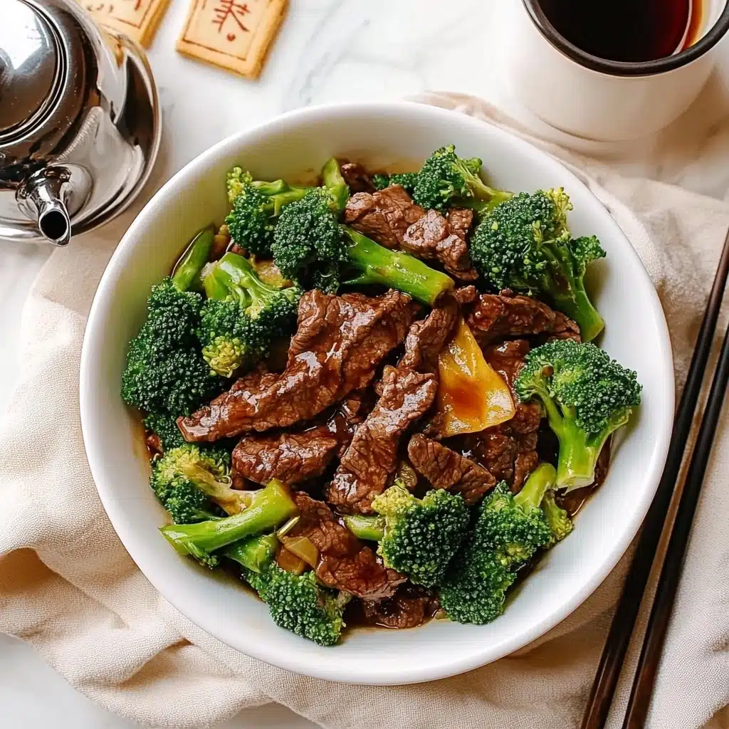 Beef and Broccoli Stir-Fry, Chinese Beef Stir-Fry, Easy Asian Beef Recipe, Quick Weeknight Dinner, Healthy Beef and Broccoli A white bowl filled with several layers of bright green broccoli florets and thick slices of shiny, brown meat coated in sauce, with the broccoli stems and pieces evenly spread around and beneath the meat. The bowl sits on a light beige cloth with frayed edges, and the background shows a blurred silver teapot and a wooden cup against a white marbled surface.