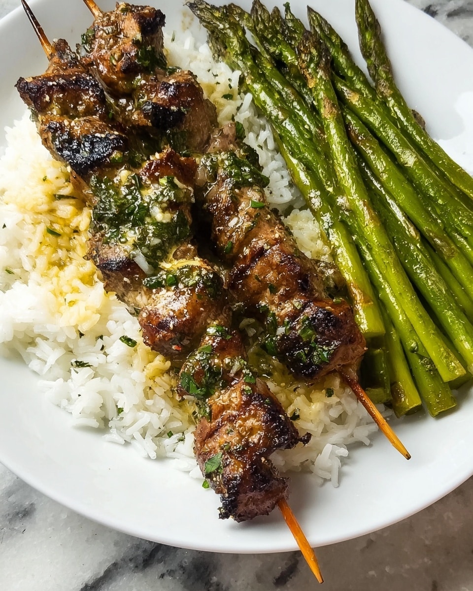 The image shows two grilled skewers with brown, slightly charred pieces of meat covered in a garlic and herb sauce, placed on a bed of white rice that forms the bottom layer of the dish. To the side of the rice and skewers is a neat pile of bright green grilled asparagus with a shiny, cooked texture. All the food is served on a white plate, and the background is a white marbled surface. photo taken with an iphone --ar 4:5 --v 7