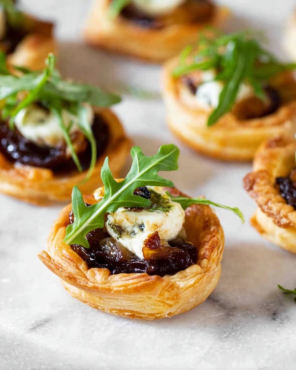 A close-up view of small square puff pastry appetizers arranged neatly in a baking tray. Each puff pastry has a golden-brown, crispy, and flaky texture with slightly raised edges. Inside each square is a layer of vibrant red tomato sauce, topped with a slice of soft white cheese that appears creamy and smooth. Some pieces also have a thin slice of purple onion and small green herb leaves scattered on top, adding color contrast and freshness. The surface beneath the tray is a white marbled texture. photo taken with an iphone --ar 4:5 --v 7