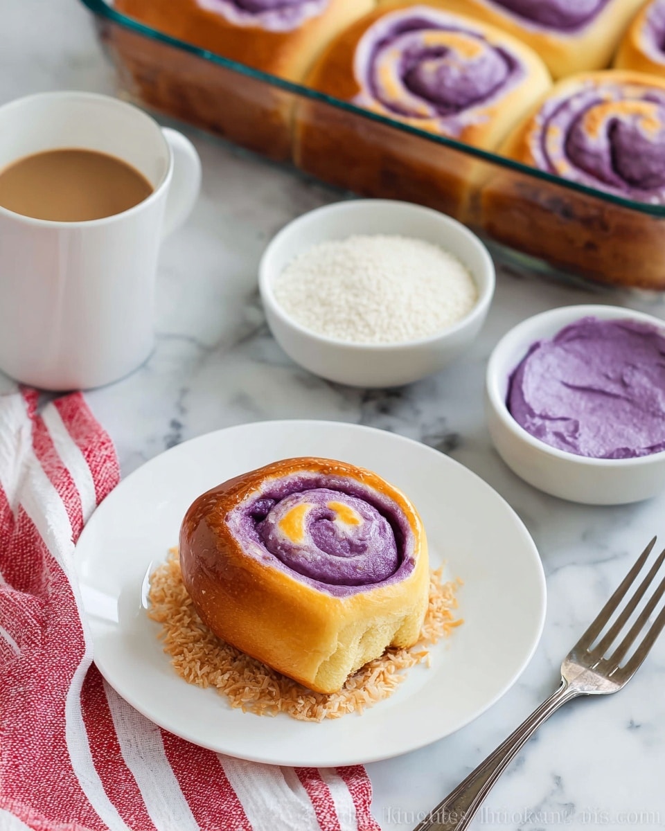 A single golden brown roll with a purple swirl inside sits on a white plate, resting on a small bed of light brown shredded topping. Behind it, there is a glass baking dish with six more rolls, each showing the same purple spiral pattern. Nearby, a small white bowl holds fine white grains, and another white bowl contains smooth purple paste. On the left side, there's a white cup of coffee with light foam on top. The setting includes a white and red striped cloth on a white marbled surface, with a fork resting at the bottom right corner. Photo taken with an iphone --ar 4:5 --v 7