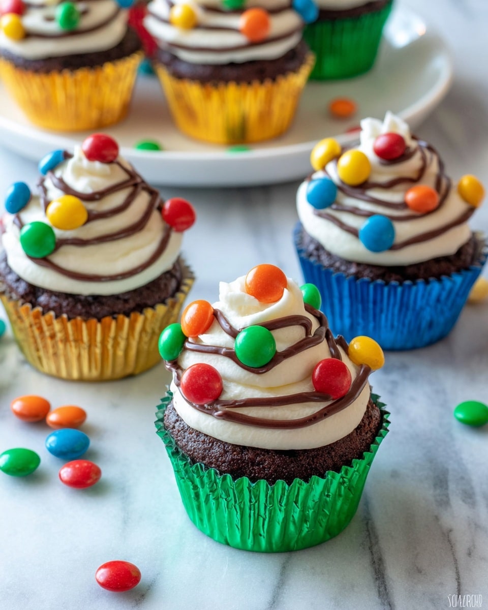 The image shows several chocolate cupcakes in shiny green, gold, and blue wrappers. Each cupcake has three layers: a dark chocolate base, a thick swirl of smooth white frosting, and a thin swirl of dark chocolate sauce on top. The frosting is decorated with colorful candy pieces in red, blue, green, yellow, and orange, evenly placed around the frosting. The cupcakes sit on a white marbled surface with some scattered colorful candies around them. In the background, more cupcakes sit on a white plate. photo taken with an iphone --ar 4:5 --v 7